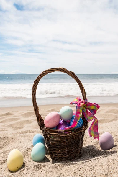 Pláž šťastné velikonoční pozadí s košíkem a barevnými vejci — Stock fotografie
