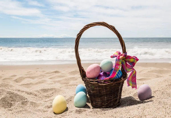 Pláž šťastné velikonoční pozadí s košíkem a barevnými vejci — Stock fotografie