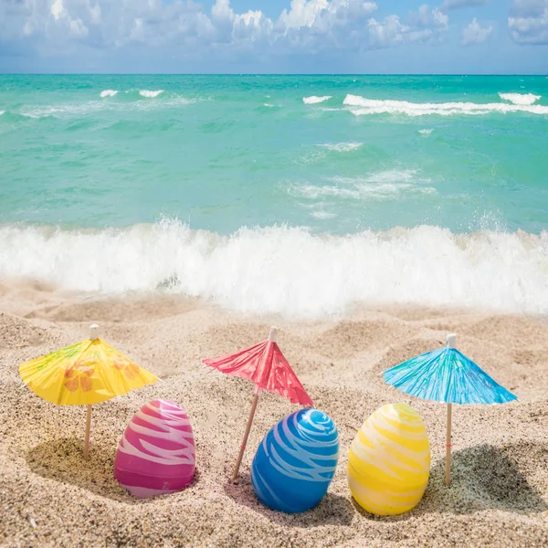 Fondo de letras de Pascua feliz con huevos en la playa de arena — Foto de Stock