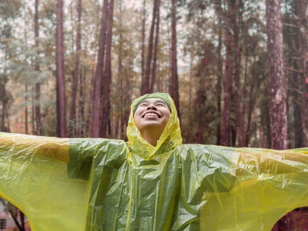 Retrato de mujer asiática feliz vistiendo impermeable amarillo de pie en r — Foto de Stock