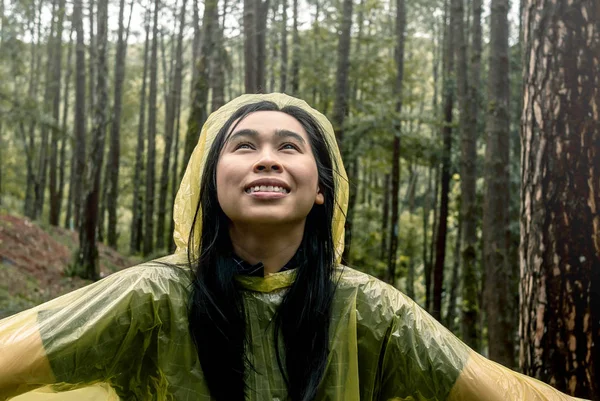 Portrait of Happy Asian woman wearing yellow raincoat stand in r