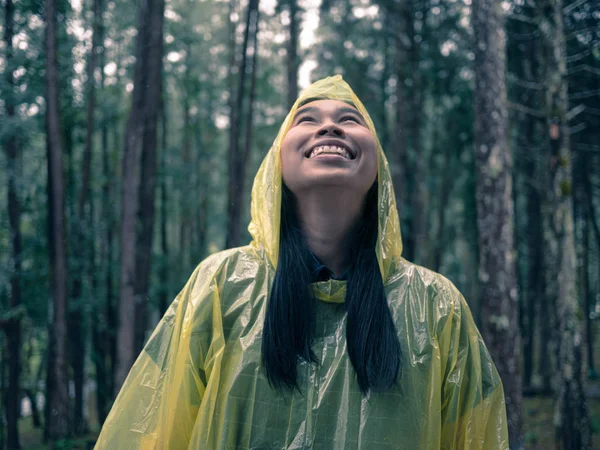 Retrato de mujer asiática feliz vistiendo impermeable amarillo de pie en r — Foto de Stock
