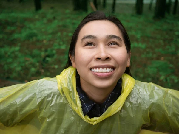 Portrait of Happy Asian woman wearing yellow raincoat stand in r