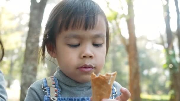 Ασιατικό Κοριτσάκι Που Απολαμβάνει Φαγητό Παγωτό Κάθεται Χόρτα Στο Πάρκο — Αρχείο Βίντεο
