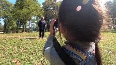 Asyalı küçük çocuk fotoğrafçı, büyükbabasının yaz parkında fotoğraflarını çekiyor. Çocuk için teknoloji ve hobi yaşam tarzı kavramları.