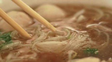 Geleneksel Vietnam usulü et çorbası Pho 'da erişte toplamak için çubuk kullan. Vietnam usulü yemek..