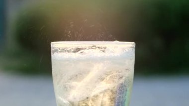 Hava kabarcığına yakın plan yeşil doğa bokeh arkaplan üzerine buzlu mineral karbonatlı su dökerken.