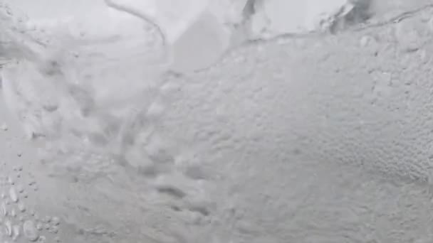 澄んだガラス中の氷とミネラル炭酸水の気泡の動き — ストック動画