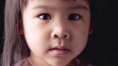 Asyalı küçük bir kızın portre yüzü. Karanlık arka plandaki kararlılığını gösteriyor..
