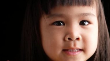 Esmer arka planda mutlu bir yüzü olan Asyalı küçük bir kızın portresi..
