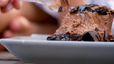 Kafedeki beyaz tabakta çikolatalı keki kepçelemek için kaşık kullanarak yakın plan çek..