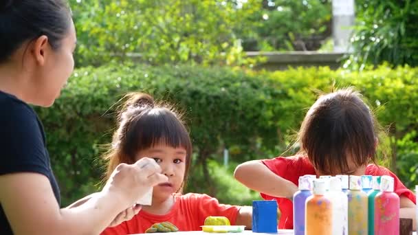 炎热的夏天 亚洲的两个小妹妹和妈妈一起 喜欢在石头和木块上涂丙烯酸漆 儿童的创造力 — 图库视频影像