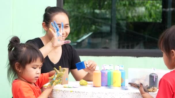 아시아의 자매는 여름날 어머니와 아크릴 페인트로 손으로 손으로 그림을 즐긴다 — 비디오