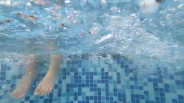 子供の足の水中シーンは ホテルの残りのゾーンでは スイミングプール内の水をはね 家族との休暇でのリラクゼーションの概念 — ストック動画