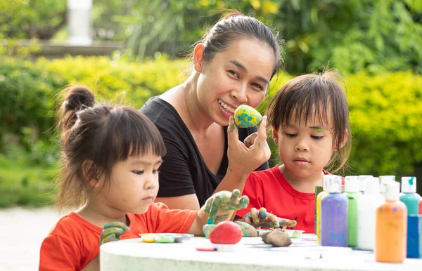 アジアの二人の妹は暑い夏の日に母と石や木のブロックにアクリル絵具で手描きで楽しむ 子供の創造性 工芸品 — ストック写真