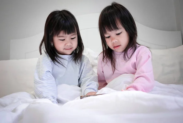 夜のベッドでスマートフォンを見ているパジャマ姿のアジアの兄弟姉妹 モバイル中毒技術の概念は — ストック写真