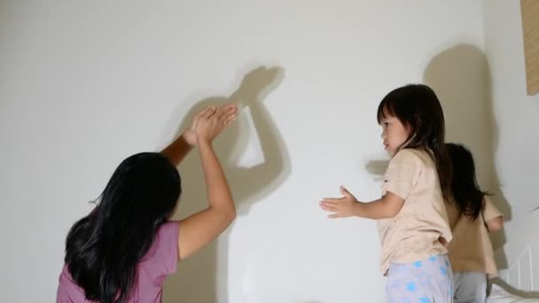 快乐的小女孩和妈妈在卧室的墙上手拿着火炬和影子玩耍 家庭和快乐时光概念 — 图库视频影像
