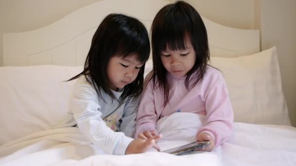 穿着睡衣的亚洲兄弟女孩在床上用智能手机玩游戏 流动成瘾技术概念 — 图库视频影像