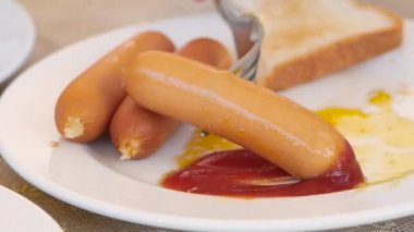 Ketçaplı sosis yiyen Asyalı kadın. Amerikan usulü kahvaltı, kızarmış yumurta ve tost..