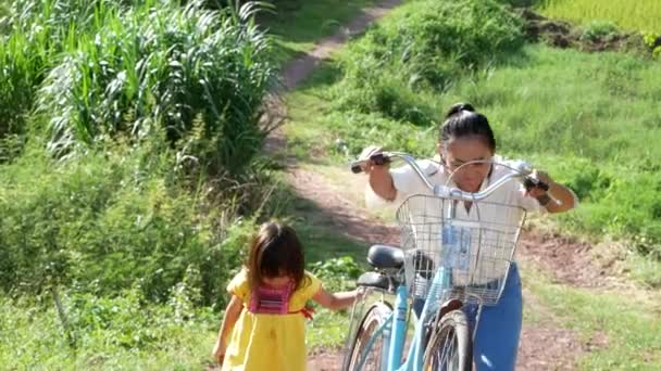 年轻的母亲和她的女儿骑自行车在室外的夏季公园里散步 度假时的放松和生活方式 — 图库视频影像