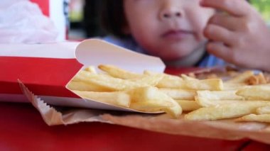 Mutlu kız çocuğu, servis atölyesinde kızarmış tavuk ve patates kızartması yemekten hoşlanır. Abur cubur ve sağlık kavramları.