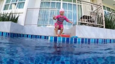Mutlu kız çocuğu suya atlıyor ve yüzme havuzuna dalıyor. Aile yaz tatili.