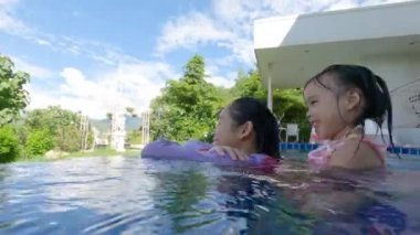 Asyalı kardeş kardeşler sıcak bir yaz gününde aileleriyle yüzme havuzunda oynuyorlar. Tatilde aile hayatı.