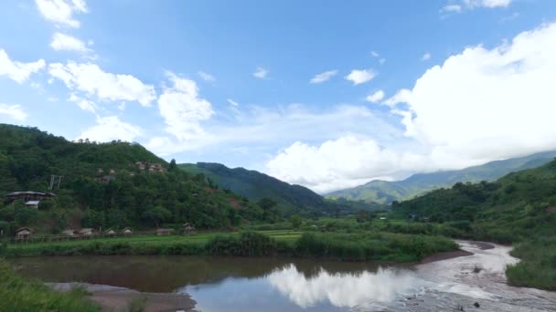 澄んだ空を背景に雲が立ち並ぶ山の風景と田園地帯を流れる川 — ストック動画