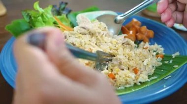 Tayland yemeği yiyen bir kadın restoranda sebze ve sosisli kızarmış pilav servis ediyor..