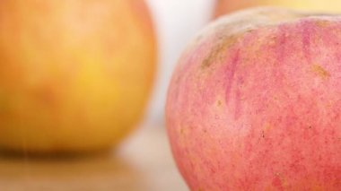 Tahta arka planda toplandıktan sonra taze su püskürten olgun elmalar..