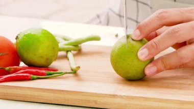 Kadın şef tahta kesme tahtasında bıçakla limonu parçalara ayırıyor..