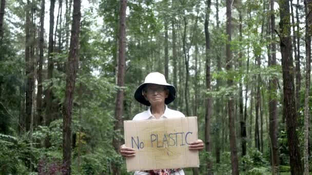 森の中に自然保護旗を掲げるシニアボランティア 世界環境デーのコンセプト 廃棄物ゼロ — ストック動画