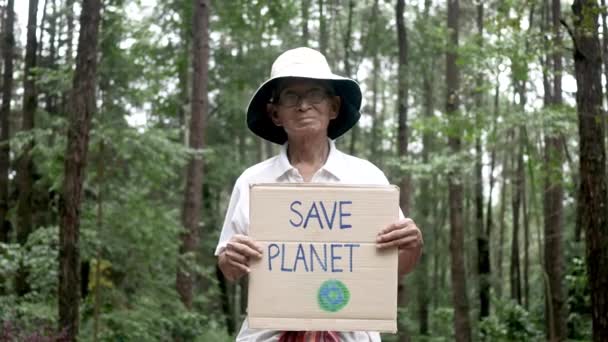 森の中に自然保護旗を掲げるシニアボランティア 世界環境デーのコンセプト 廃棄物ゼロ — ストック動画