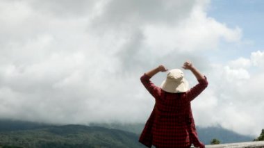 Başarıyı ifade eden kadın, elleri dağın zirvesinde, gökyüzü arka planında. Başarı ve kazanma kavramı.