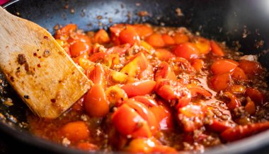 Tayland 'ın kuzeyindeki ünlü yiyecekler. Ana bileşenler domates ve domuz eti. Tavada kırmızı köri ezmesine (Nam Prik Ong) yakın plan domatesler.