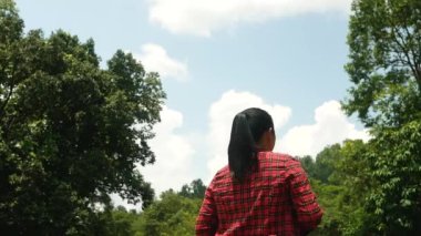 Kollarını açmış, ormanda akan su ve doğanın tadını çıkaran mutlu bir kadın turist..