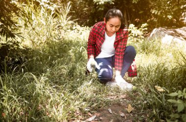 Gönüllü kadın parkta oturur ve çöpleri toplar. Çevre plastik kirliliği. Dünya Çevre Günü konsepti. Sıfır atık.