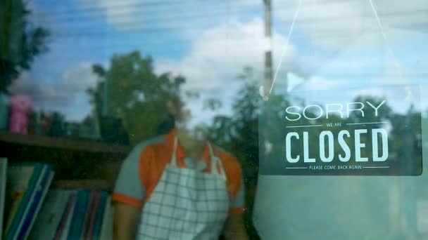 アジア系女性の店主が玄関に掛かる店のオープニングを示す看板を回している ウイルス発生後に業務を再開する事業 — ストック動画