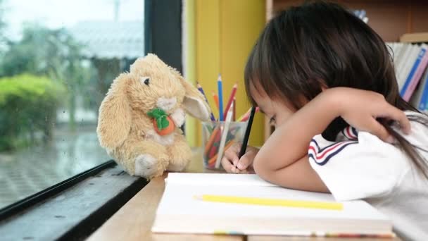 귀여운 소녀가 집에서 종이에 연필로 그림을 그리고 — 비디오