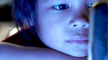 Küçük kızın gece yatağında akıllı telefona bakarken mavi ışığın çocukların gözleri üzerinde olumsuz bir etkisi oluyor..