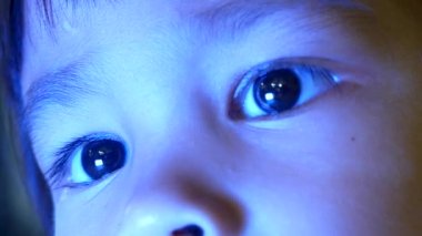 Küçük kızın gece yatağında akıllı telefona bakarken mavi ışığın çocukların gözleri üzerinde olumsuz bir etkisi oluyor..