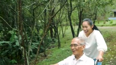 Mutlu büyükbaba tekerlekli sandalyede rahatlıyor ve torunuyla parkta yürüyor. Aile mutlu bir yaşam tarzı.