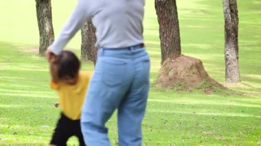 Mutlu anne ve çocuklar bahçede yeşil çimlerde oturup oynuyorlar. Rahatlama zamanı ve aile ilişkisi kavramları.