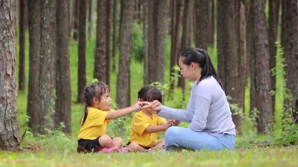 快乐的母亲和孩子们坐在花园里绿色的草坪上玩耍 放松时间和家庭关系的概念 — 图库视频影像