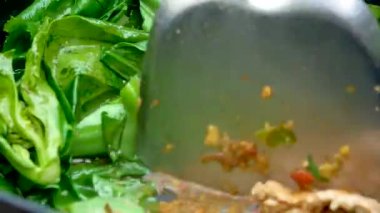 Kadının ellerinin kızartma tavasında kızarmış lahana, kırmızı biber, istiridye sosu ve mutfaktaki gazdan çıkan acı ateşte pişmiş şeker pişirirken yakın plan. Lezzetli Tayland yemekleri..