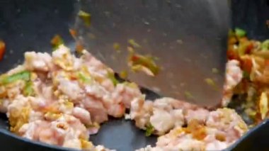 Kızarmış kırmızı biber ve sarımsağı kızartılmış tavada kızartılmış domuz etiyle pişiren bir kadının ellerini yakın. Lezzetli Tayland yemekleri. Basil Yapraklarıyla Kızarmış Domuz Etini Karıştır.