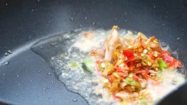Mutfaktaki gazdan kızgın tavada kızarmış kırmızı biber ve sarımsak pişiren kadınların ellerini yakın. Lezzetli Tayland yemekleri. Basil Yapraklarıyla Kızarmış Domuz Etini Karıştır.