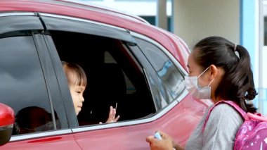 Tıbbi maskeli küçük bir kız ve anne. Anne kalabalık bir yerde Coronavirus ve grip enfeksiyonuna karşı korunmak için kızına yüz maskesi takıyor.. 