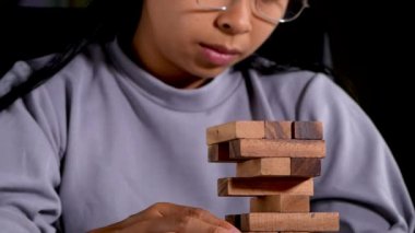 Bir kadın odada tek başına ahşap bloklar çıkarmaya odaklanıyor ve düşünüyor. Jenga masaya düşer. İş hayatında başarı ve başarısızlık kavramı.