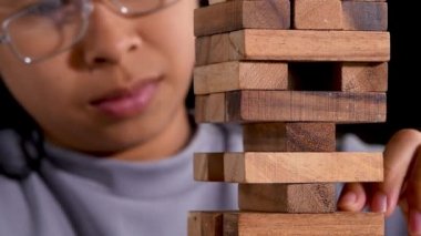 Bir kadın odada tek başına ahşap bloklar çıkarmaya odaklanıyor ve düşünüyor. Jenga masaya düşer. İş hayatında başarı ve başarısızlık kavramı.